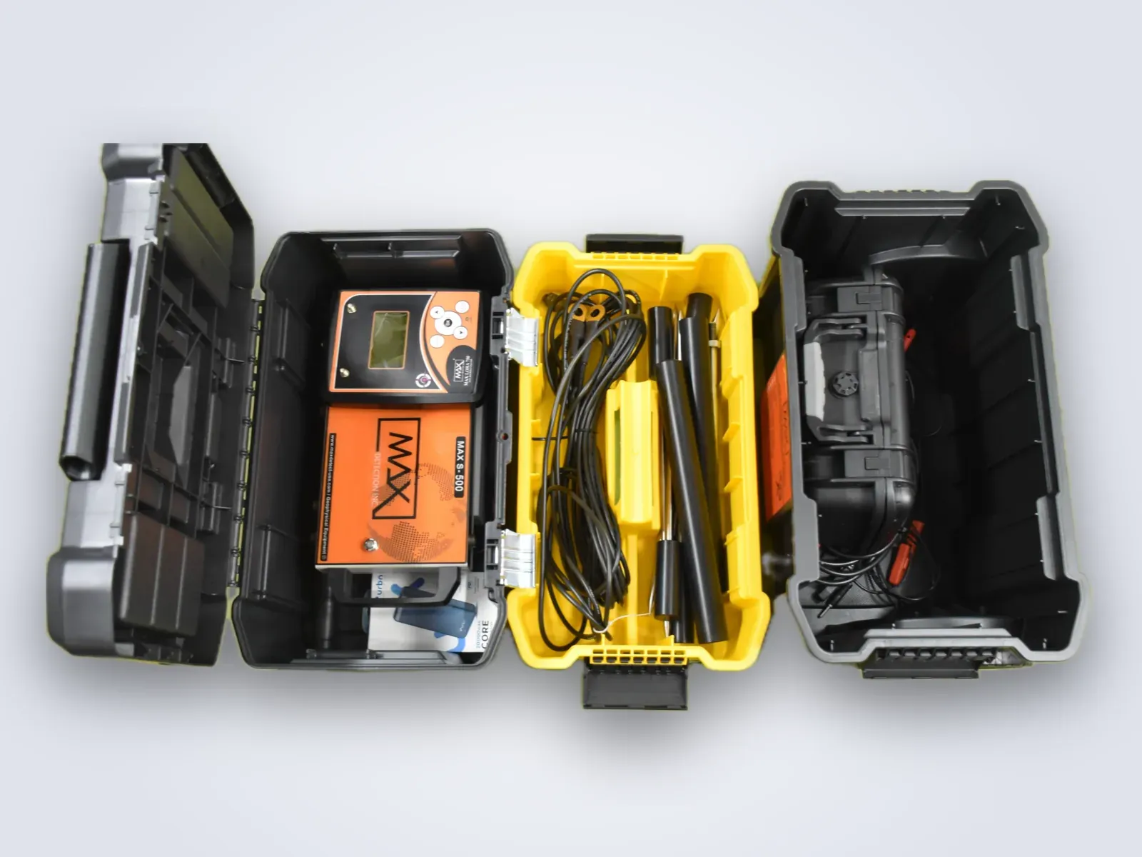 The three tiers of the case opened and laid side by side, seen from above - the Lora 750 console and orange S-500 host unit in the top box, cables and electrode rods in the middle tray, the ADS-IP hard case in the bottom bin